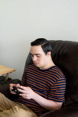 young adult with down syndrome playing video games in couch