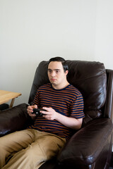 Obraz premium young adult with down syndrome playing video games in couch