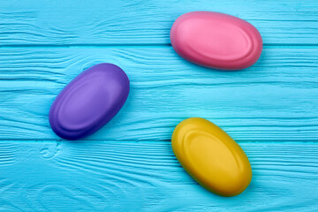Obraz na płótnie Canvas Three colored pieces of soap on blue wooden background.