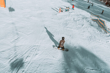 People in winter enjoying the snowy mountains where are practised plenty of activities such as skiing and snowboarding with a clear sky and some clouds on the horizon.