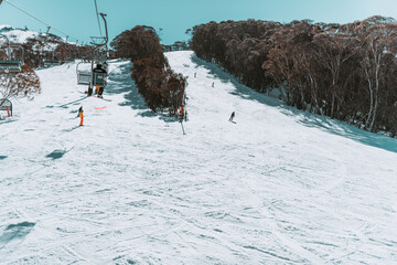 People in winter enjoying the snowy mountains where are practised plenty of activities such as skiing and snowboarding with a clear sky and some clouds on the horizon.