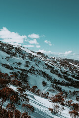 People in winter enjoying the snowy mountains where are practised plenty of activities such as skiing and snowboarding with a clear sky and some clouds on the horizon.