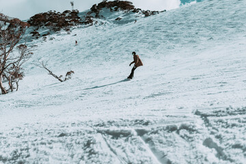 People in winter enjoying the snowy mountains where are practised plenty of activities such as skiing and snowboarding with a clear sky and some clouds on the horizon.