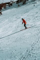 People in winter enjoying the snowy mountains where are practised plenty of activities such as skiing and snowboarding with a clear sky and some clouds on the horizon.