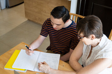 Mom helping young teenager son with online home schooling