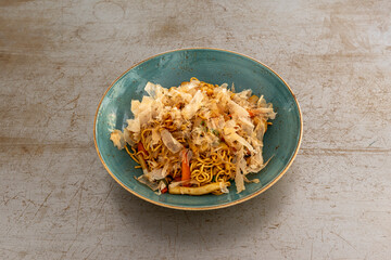 Yakisoba noodles with chicken and vegetables cooked in the wok on scratched metal table