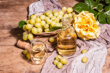 White wine and grape in a wicker basket on wooden table