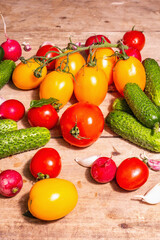 Assortment of ripe organic farmer red and yellow tomatoes, cucumbers, radish, garlic, and fresh basil leaves