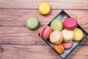 french dessert macarons of different colours on a wooden background 