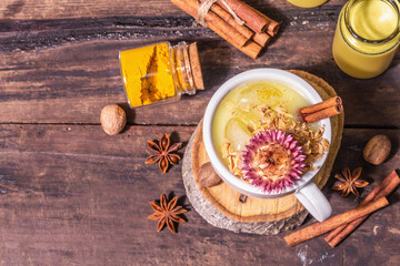 Golden turmeric milk with ice on bright yellow background