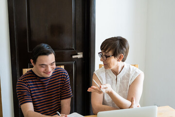 Adult mature mom helping young son with online home school