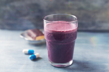 Glass of Protein Shake with milk and blueberries and Creatine capsules. Concept for Sport...