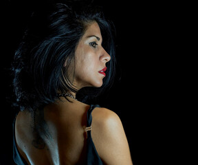 black-haired brunette latina girl with bare back, attractive. black background, horizontal. copy...