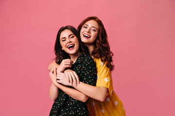 Charming ladies look into camera and hug. Fashionable women in great polka dot dresses have fun...