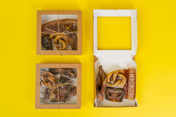 Kit of dried meat treats for training and encouraging dogs in recyclable eco-friendly cardboard boxes, top view, yellow background, copy space.