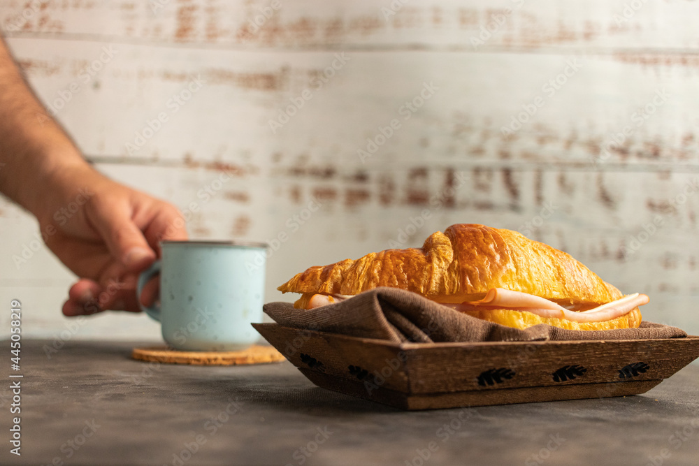 Poster crunchy delicious croissant with ham and cheese filling and a mug of hot coffee on a table