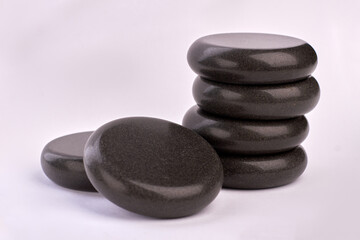 Polished black stones for spa treatment therapy on white background.