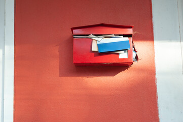 red mailbox with documents overflowing