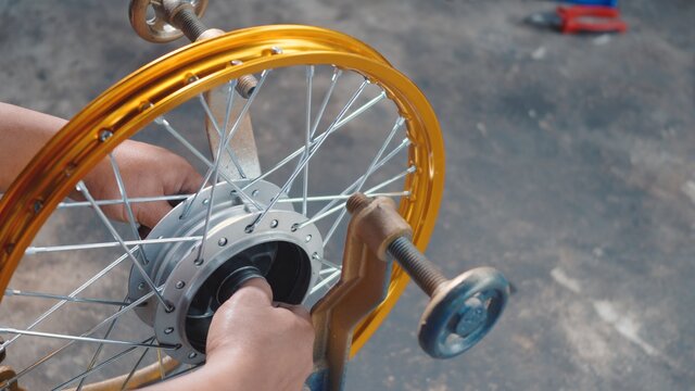 Technician man working motorcycle wheel has spokes weave up on mechanic new steel wheel, Motorcycle spokes wheel alignment machine tool - Powered by Adobe