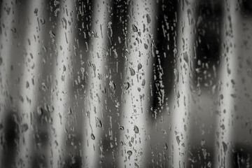 Black and white glass window with water droplets after rainfall