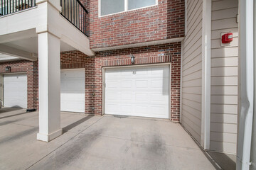 Three white sectional garage doors of a building with bricks