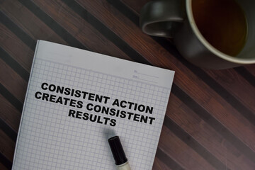 Consistent Action Creates Consistent Results write on a book isolated on Wooden Table.