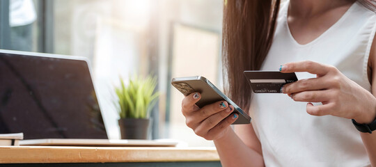 Fototapeta premium Pay for goods by credit card through a smartphone in a coffee shop.