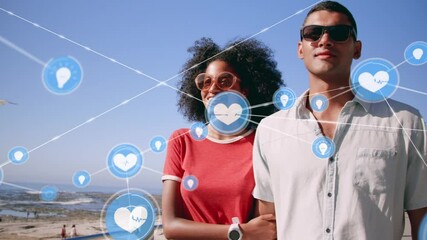 Network of digital icons against mixed race couple holding hands walking on the beach - Powered by Adobe