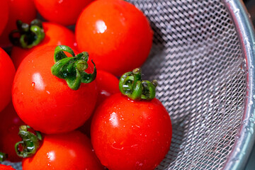 Close-up of a fresh red cherry tomato in a colander