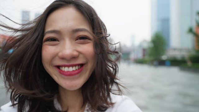 happy young asian woman close up portrait slow motion charming Chineses lady lovley girlfriend looking at camera smile in the urban city street