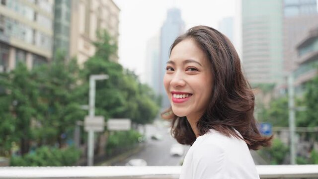 beautiful young Asian woman Turn around and look at the camera and smile in the urban city street then walk away