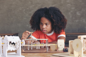 A serious afro teen girl curly hair style Staring at the parts of the simulation mechanism robot...