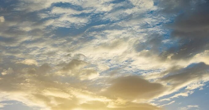Timelapse of golden fluffy clouds moving on the blue sky in sunset