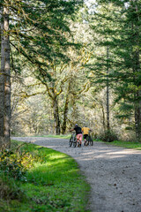 Obraz premium Two friends push their mountain bikes up a wide forest path