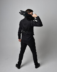 Full length portrait of a  brunette man wearing leather jacket  and holding a science fiction gun. ...