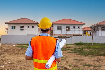 Asian man civil engineer paper plan building architect wearing white safety helmet look at the construction site.