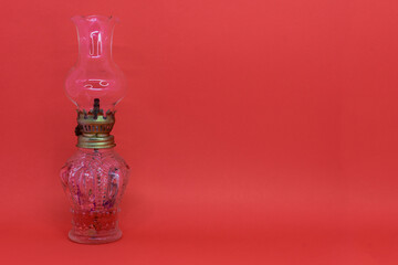 Antique glass, decorative kerosene lamp isolated on red background. Space to place text