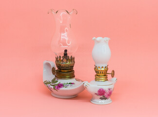 Two antique decorative kerosene lamps isolated on salmon pink background. horizontal close-up
