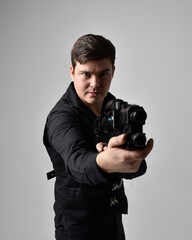 close up portrait of a  brunette man wearing leather jacket  and holding a science fiction gun.  action pose isolated  against a grey studio background.