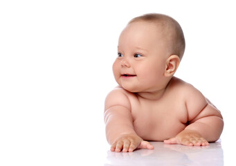 Smiling, giggling playful infant child baby girl kid in diaper is lying on her tummy holding arm outstretched, slapping on floor, looking aside isolated on a white background