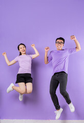 Young Asian couple jumping on purple background