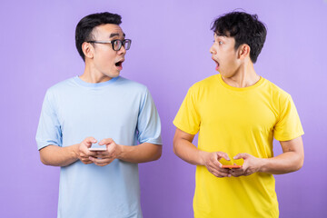 Two Asian brothers using cell phones on purple background