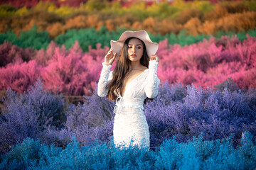An Asian woman in a white dress poses in a colorful meadow