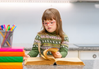A girl with Down Syndrome is exercising on-line using a tablet at home. Remote education for people with disabilities