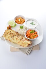 Indian baked roti prata canai with curry vegetables, yogurt sauce, pea bean and steamed white rice in white background asian vegan halal menu
