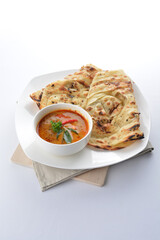 indian roti prata canai 2 pieces with spicy curry chicken gravy soup in bowl in white background asian halal menu