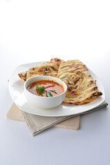 indian roti prata canai 2 pieces with spicy curry chicken gravy soup in bowl in white background asian halal menu