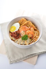 spicy nyonya noodle laksa soup with seafood prawn, fish cake, egg, bean curd and chilli sambal sauce in white background asian halal menu