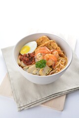 spicy nyonya noodle laksa soup with seafood prawn, fish cake, egg, bean curd and chilli sambal sauce in white background asian halal menu