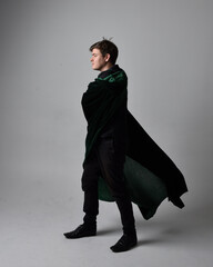 Full length portrait of a  brunette man wearing black shirt, waistcoat and a green velvet cloak. ...